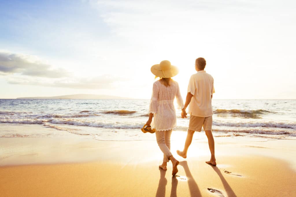 Pareja paseando al atardecer por la orilla del mar de una playa en la Costa Blanca.